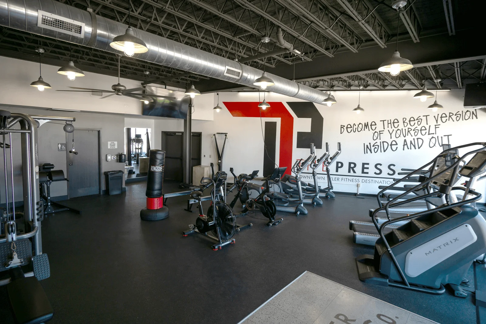 Main gym floor with giant TP mural, motto, and Matrix ClimbMill